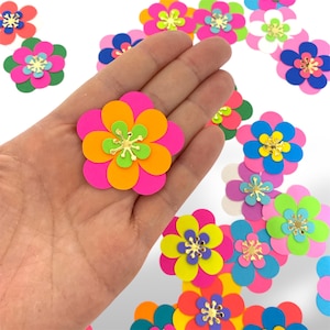 May include: Assortment of colorful paper flowers with gold centers. The flowers are layered and have a retro, 70s aesthetic.