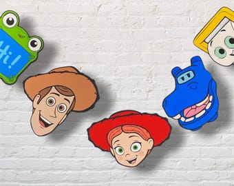 Puede incluir: Una colección de cinco pegatinas de pared coloridas con personajes, que incluyen una rana verde con el texto Hi!, un personaje con sombrero de vaquero marrón, un personaje con sombrero rojo, un hipopótamo azul y un rostro enmarcado en amarillo.