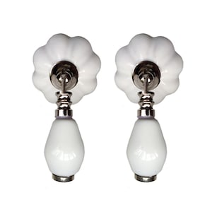 Könnte beinhalten: Zwei weiße Keramik-Schrankknöpfe mit tropfenförmigem Sockel und geriffeltem Oberteil.