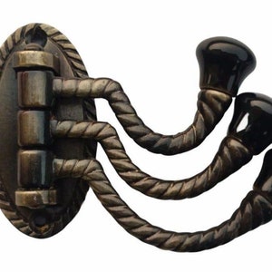 May include: A triple hook wall mount with a decorative rope design. The hooks are made of metal and have black ceramic finials. The base is oval shaped and has a rope design around the edge.