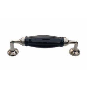 May include: Black ceramic cabinet pull with silver metal accents. The pull has a curved shape and is designed for use on cabinets and drawers.