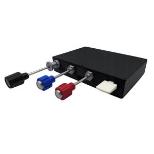Könnte beinhalten: Eine schwarze, rechteckige elektronische Steuerbox mit drei hervorstehenden Metallhebeln, die mit schwarzen, blauen und roten zylindrischen Knöpfen versehen sind, sowie einem einzelnen weißen rechteckigen Schalter an der Seite des Gehäuses.