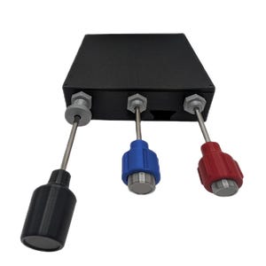 Può includere: Una scatola di controllo elettronica rettangolare nera con tre aste metalliche sporgenti. Ogni asta è sormontata da una manopola cilindrica rispettivamente nera, blu e rossa. Le aste sono fissate alla scatola con dadi esagonali grigi.
