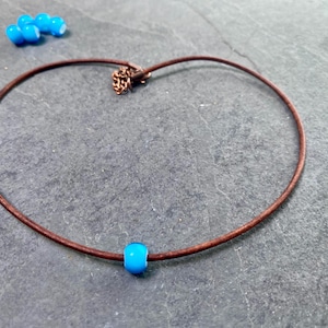 A minimalist surfer girl necklace featuring a translucent blue 4mm white heart bead.