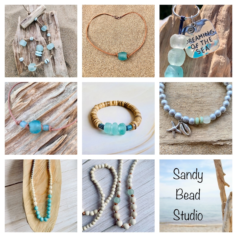 May include: A collection of handmade jewelry featuring sea glass and wood beads. The jewelry includes necklaces, bracelets, and a keychain. The jewelry is displayed on a wooden background with a beach theme. The text "Dreaming of the Sea" is on the keychain.