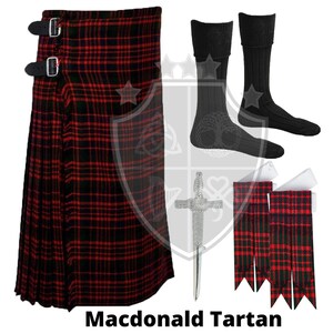 K&ouml;nnte beinhalten: Ein roter, schwarzer und gr&uuml;ner Kilt mit einer silbernen Kiltnadel. Der Kilt ist aus traditionellem Tartanstoff gefertigt. Zum Kilt geh&ouml;ren ein Paar schwarze Socken, ein Set roter und schwarzer Kiltstr&uuml;mpfe und ein wei&szlig;er Kiltg&uuml;rtel.