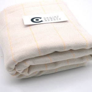 May include: A folded piece of white fabric with thin yellow stripes. The fabric is labeled "CPOINT PUNCH NEEDLE".