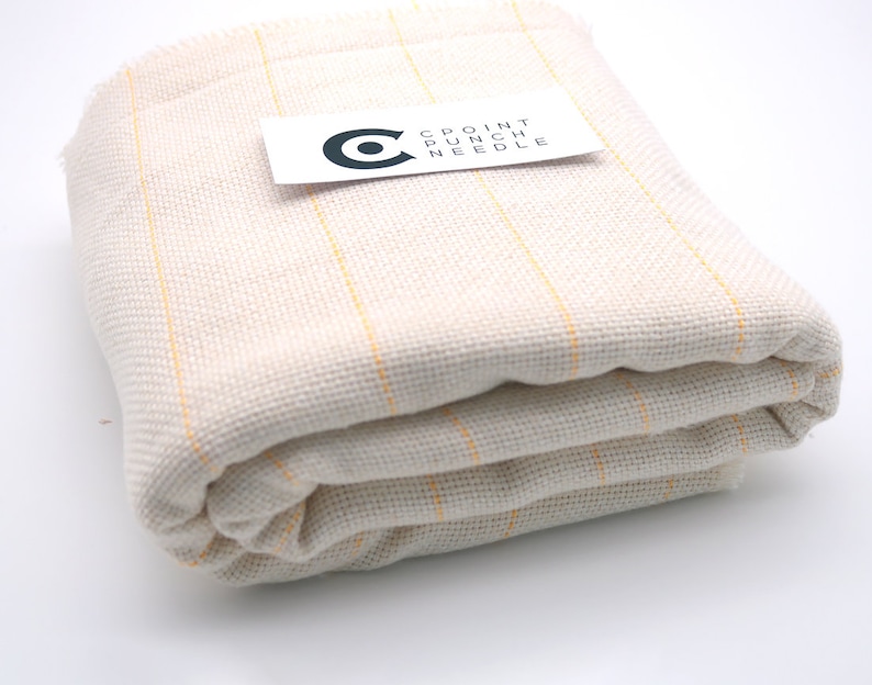 May include: A folded piece of white fabric with thin yellow stripes. The fabric is labeled "CPOINT PUNCH NEEDLE".