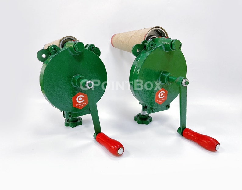 May include: Two green manual paper roll holders with red handles. Each holder has a cardboard roll and a crank to wind the roll. The holders have a red logo with the text "C POINTBOX".
