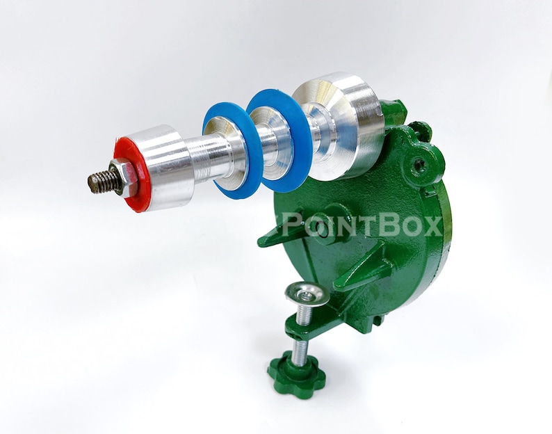 May include: A green metal tool with a silver and red handle and blue and red rings. The tool is mounted on a green base with a clamp.