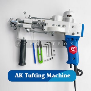 Può includere: Una macchina per tufting elettrica blu e bianca con un'impugnatura nera e un pedale. La macchina è su una superficie bianca con un set di strumenti e viti. Il testo "AK Tufting Machine" è su uno striscione blu sotto la macchina.