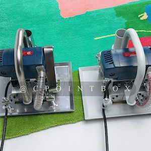 May include: Two blue and white electric carpet tufting machines with silver handles and white cords on a green and pink carpet.
