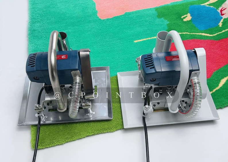 May include: Two blue and white electric carpet tufting machines with silver handles and white cords on a green and pink carpet.