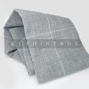 以下が含まれることがあります： グレーと白のチェック柄の生地で、織り目がざらざらしています。生地は折り畳んで丸められており、柔らかく、魅力的な外観になっています。