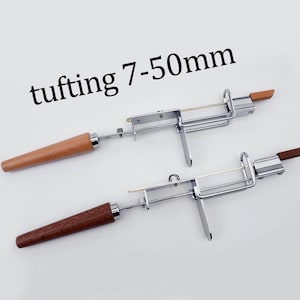 Puede incluir: Dos herramientas para mechones con mangos de madera y marcos de metal. El texto "tufting 7-50mm" está encima de las herramientas. Los mangos son de color marrón claro y marrón oscuro.