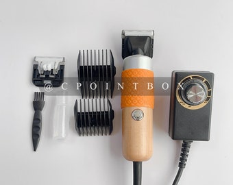 May include: A set of electric hair clippers with a wooden handle, orange and silver accents, and a black power cord. The set includes four different clipper attachments, a cleaning brush, and a bottle of oil.