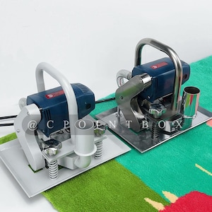 May include: Two electric carpet shears with blue and gray handles and silver bases. The shears are on a green and pink patterned carpet.