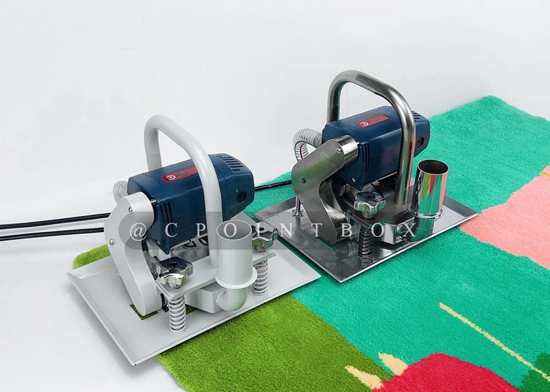 May include: Two electric carpet shears with blue and gray handles and silver bases. The shears are on a green and pink patterned carpet.