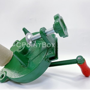 May include: Green metal hand crank machine with a brown cardboard tube inserted into the machine. The machine has a metal handle and a star-shaped knob.