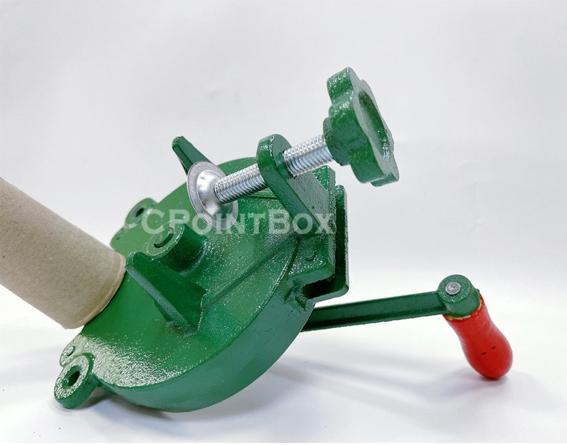 May include: Green metal hand crank machine with a brown cardboard tube inserted into the machine. The machine has a metal handle and a star-shaped knob.