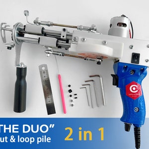 Può includere: Uno strumento elettrico blu e bianco con un'impugnatura nera. Lo strumento ha un'etichetta rossa e bianca che dice "C POINTBOX" e "THE DUO" cut & loop pile 2 in 1. Lo strumento è su una superficie bianca con un righello, uno strumento rosa e alcuni piccoli pezzi neri e bianchi.