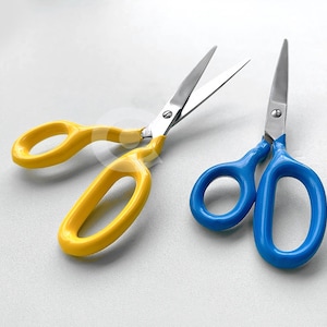 Puede incluir: Dos pares de tijeras con mangos de plástico amarillo y azul. Las tijeras amarillas tienen una hoja plateada y las tijeras azules tienen una hoja plateada.