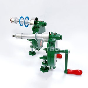 May include: A green metal hand crank machine with a silver rod and a red handle. The machine has two sets of blue and silver rings.