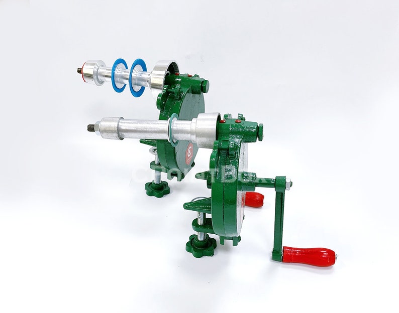 May include: A green metal hand crank machine with a silver rod and a red handle. The machine has two sets of blue and silver rings.