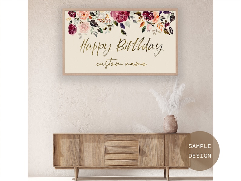 Puede incluir: Un letrero enmarcado con las palabras "Happy Birthday" en escritura dorada, con espacio para un nombre personalizado. La parte superior del letrero est&aacute; decorada con flores de acuarela en tonos rosa, burdeos y naranja.