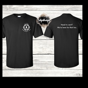 May include: Black t-shirt with white text and graphics. The front features a ribbon and DNA strand design with the words "A EASY HEMATOLOGY AMT". The back says "Need to vent? We're here for that too."