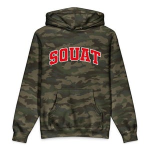 May include: A camouflage print hooded sweatshirt featuring a front kangaroo pocket and long sleeves. The word SQUAT is printed across the chest in a bold, arched red font with a white outline, set against the dark green, brown, and black pattern.