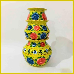 May include: Three yellow, hand-painted pots stacked on top of each other, decorated with red and blue roses and green leaves. The rims and bases have small red dots. The background is white. The pots are likely made of ceramic.