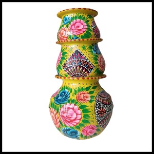 May include: A yellow, stacked decorative pot with a floral design. The pot features pink, blue, and white flowers with green leaves. The pot has a unique shape and is hand-painted with intricate details.