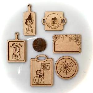 May include: Set of seven small wooden cutting boards with various Halloween-themed designs. The designs include a witch, a ghost, a spider web, a pumpkin, and a Peanuts character.