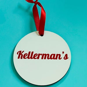 May include: White round bauble with a red ribbon and the text "Kellerman's" in red cursive lettering.