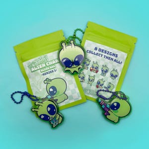 May include: Green blind bag with a green alien character keychain. The bag has the text "Arcade Bandits Alien Char Blind Bag -Series 1- 8 Designs Collect Them All!" printed on it.
