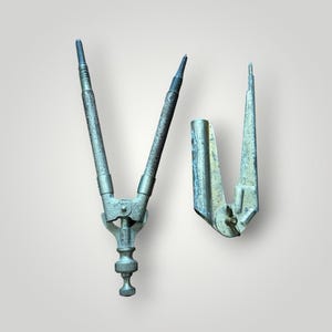 May include: Two antique drafting tools, a compass and a divider, are displayed against a neutral background. The compass has two adjustable arms with pointed tips, connected at the top with a screw mechanism. The divider has a single pointed tip.
