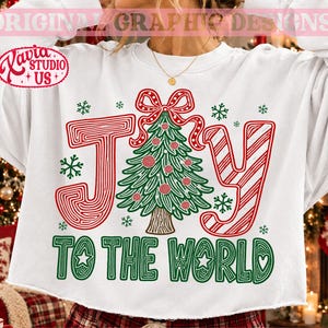 以下が含まれることがあります： JOY TO THE WORLDという文字がプリントされた白い長袖スウェットシャツ。Oの文字は、赤いオーナメントと赤いリボンが付いた緑色のクリスマスツリーに置き換えられています。文字は赤と白のストライプと緑色で構成されています。