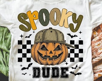 May include: White t-shirt featuring a Halloween-themed graphic. The design includes the word "SPOOKY" in orange, green, and tan letters above a jack-o'-lantern wearing a cap. The word "DUDE" is below the pumpkin, with bats and stars.