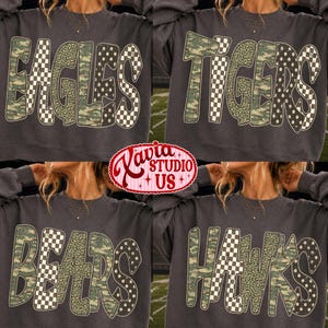 May include: A charcoal grey crewneck sweatshirt featuring large block letters that spell out team names like EAGLES, TIGERS, BEARS, or HAWKS. Each letter is filled with a mix of camouflage, black and white checkerboard, and leopard print patterns.