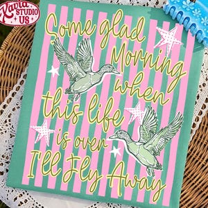 May include: A decorative canvas print featuring a teal background with pink vertical stripes. The print includes two illustrations of ducks in flight, white stars, and the text "Some glad Morning when this life is over I'll Fly Away."