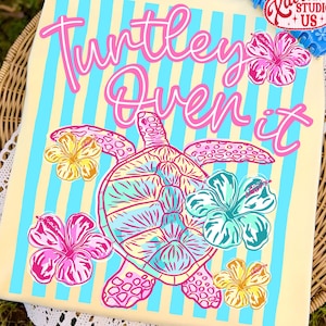 May include: A decorative rectangular item with a light yellow background and blue vertical stripes. The text "Turtley Oven it" is written in pink script. A turtle and hibiscus flowers in pink, blue, and yellow are featured.