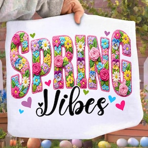 Puede incluir: Coj&iacute;n blanco con las palabras "SPRING VIBES" en letras florales. Las letras est&aacute;n llenas de varias flores y rodeadas de un ribete rosa. Peque&ntilde;os corazones de diferentes colores est&aacute;n dispersos alrededor del texto.