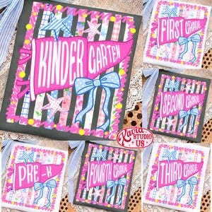 May include: A white t-shirt featuring a pink pennant flag graphic with the text "KINDERGARTEN", "FIRST GRADE", "SECOND GRADE", "THIRD GRADE", "FOURTH GRADE", or "PRE-K". The design includes a blue polka dot bow, stars, and vertical stripes.