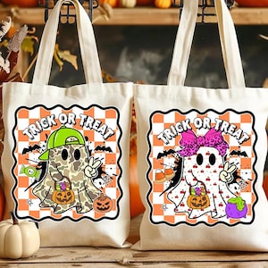May include: Two off-white canvas tote bags with Halloween-themed designs. One features a ghost in a camo pattern and a green cap, the other a ghost with a pink bow. Both say "Trick or Treat" with bats and candy.