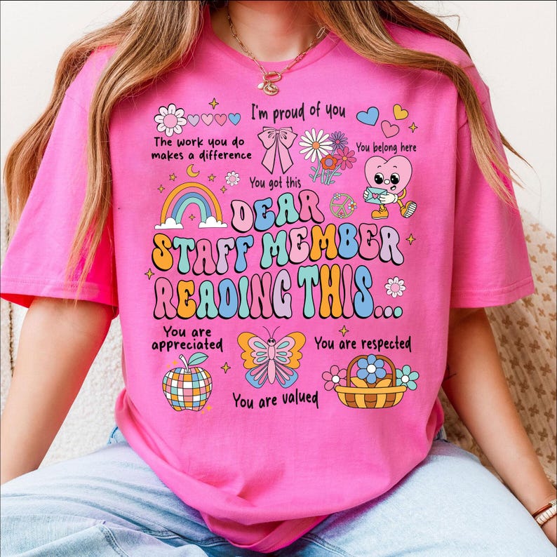 May include: Pink t-shirt with a retro design that says "Dear Staff Member Reading This..." with hearts, flowers, butterflies, and rainbows. The text says "I'm proud of you", "You got this", "You are appreciated", "You are respected", and "You are valued".