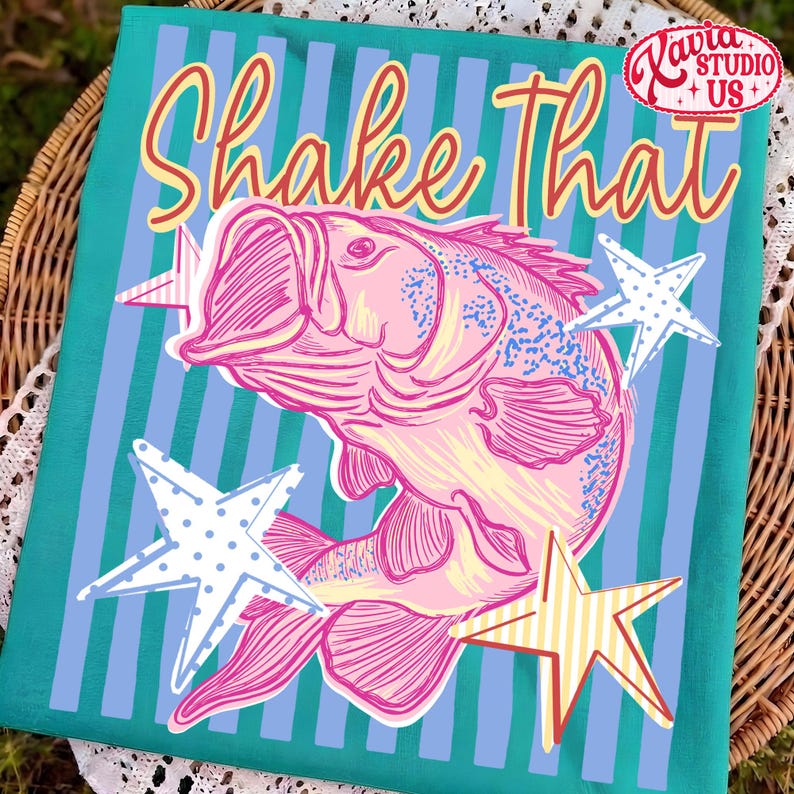 May include: A teal fabric with a pink fish illustration and the words "Shake That" in a retro font. The design includes white, blue, and yellow stars. The image has a vintage, nautical theme.