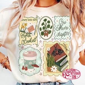May include: Cream-colored t-shirt with a collage of book-themed illustrations. Designs include a coffee cup, potted plant, open book, and the words "Fully Booked" and "One More Chapter". The shirt has a floral and botanical theme.