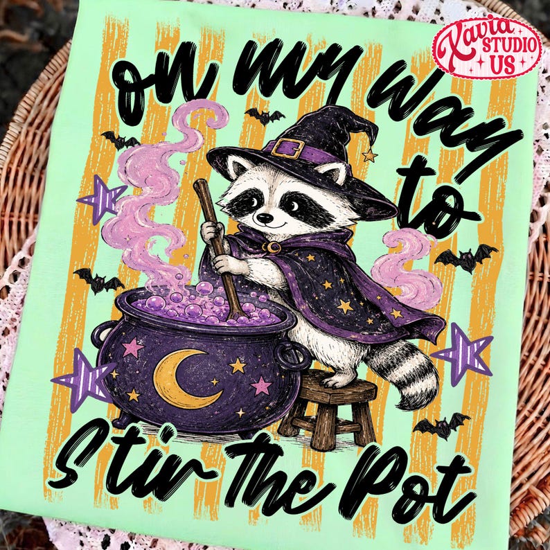 Peut inclure: Un t-shirt vert clair avec un motif de raton laveur portant un chapeau et une cape de sorcier violets, remuant un chaudron violet avec une cuill&egrave;re en bois. Le texte indique "on my way to STIR THE POT" avec des rayures orange, des chauves-souris et des &eacute;toiles.