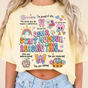 May include: A yellow t-shirt with a colorful graphic that says "Dear Staff Member Reading This..." with illustrations of hearts, flowers, butterflies, and rainbows. The text says "You are appreciated, You are respected, You are valued".